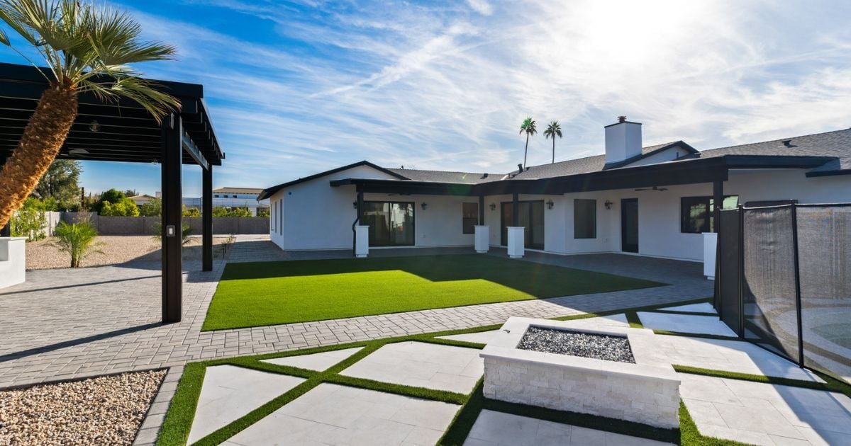 Backyard of a Scottsdale custom home by Trinity Homes AZ featuring a modern fire pit, artificial turf, and sleek pergola