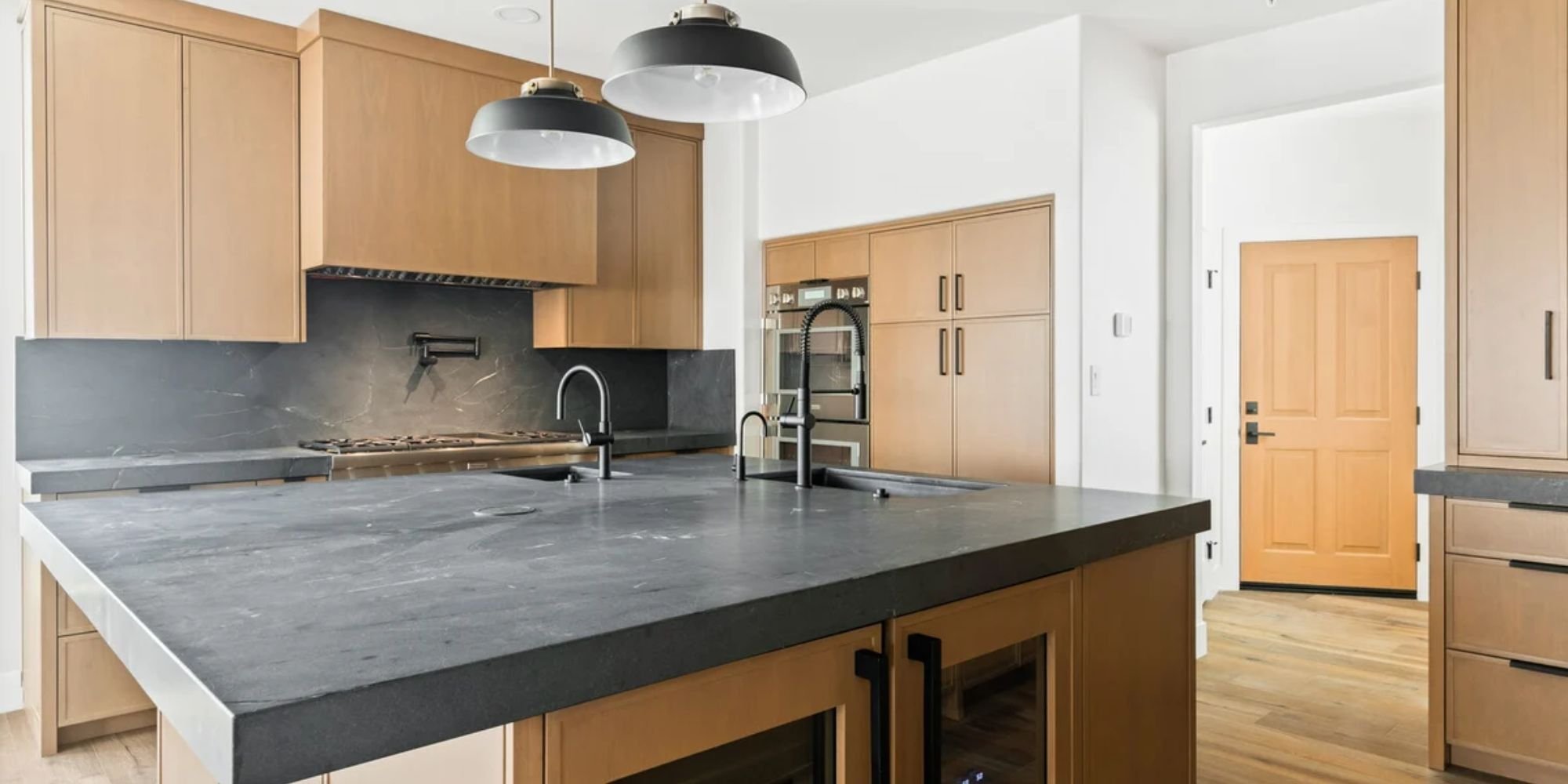 Custom kitchen in Scottsdale AZ custom home by Trinity Homes AZ, featuring light wood cabinetry and black stone countertops