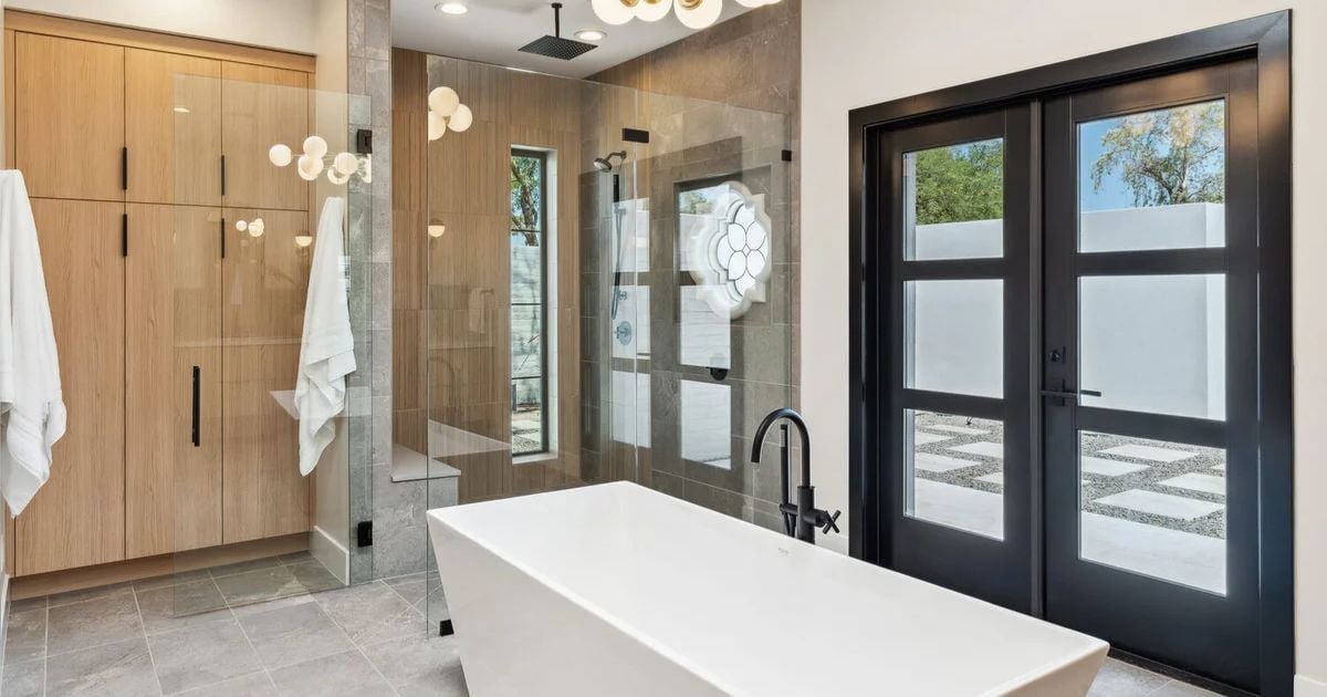 Modern freestanding bathtub and glass shower in a luxury whole home remodel by Trinity Homes in Arizona