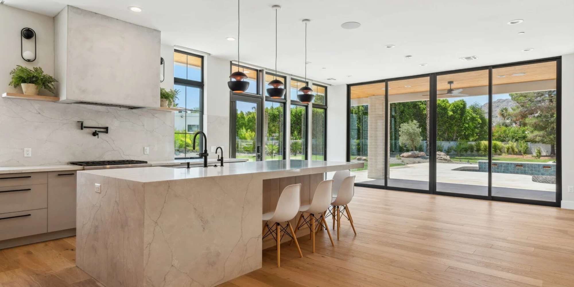kitchen addition with marble island, pendant lights, and glass doors to pool and garden by Trinity Homes AZ