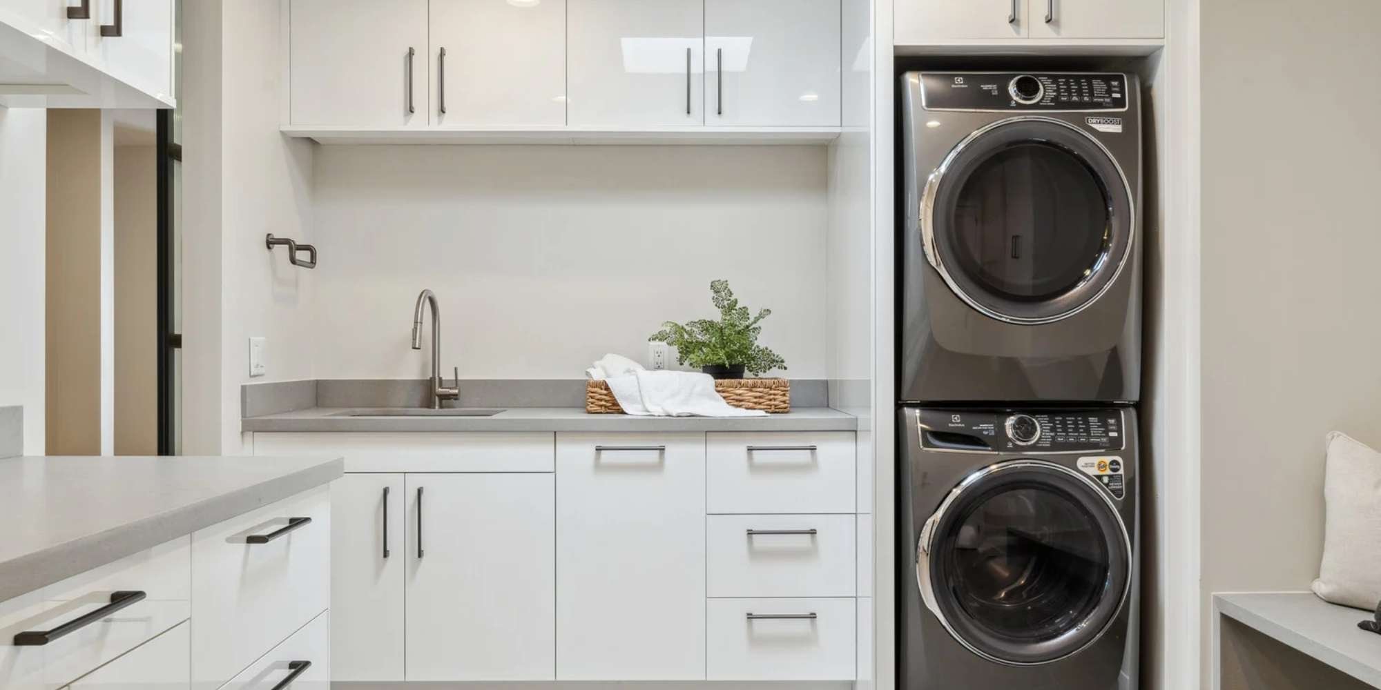 modern laundry room with white cabinets, gray countertops, and stacked washer and dryer in Scottsdale, AZ