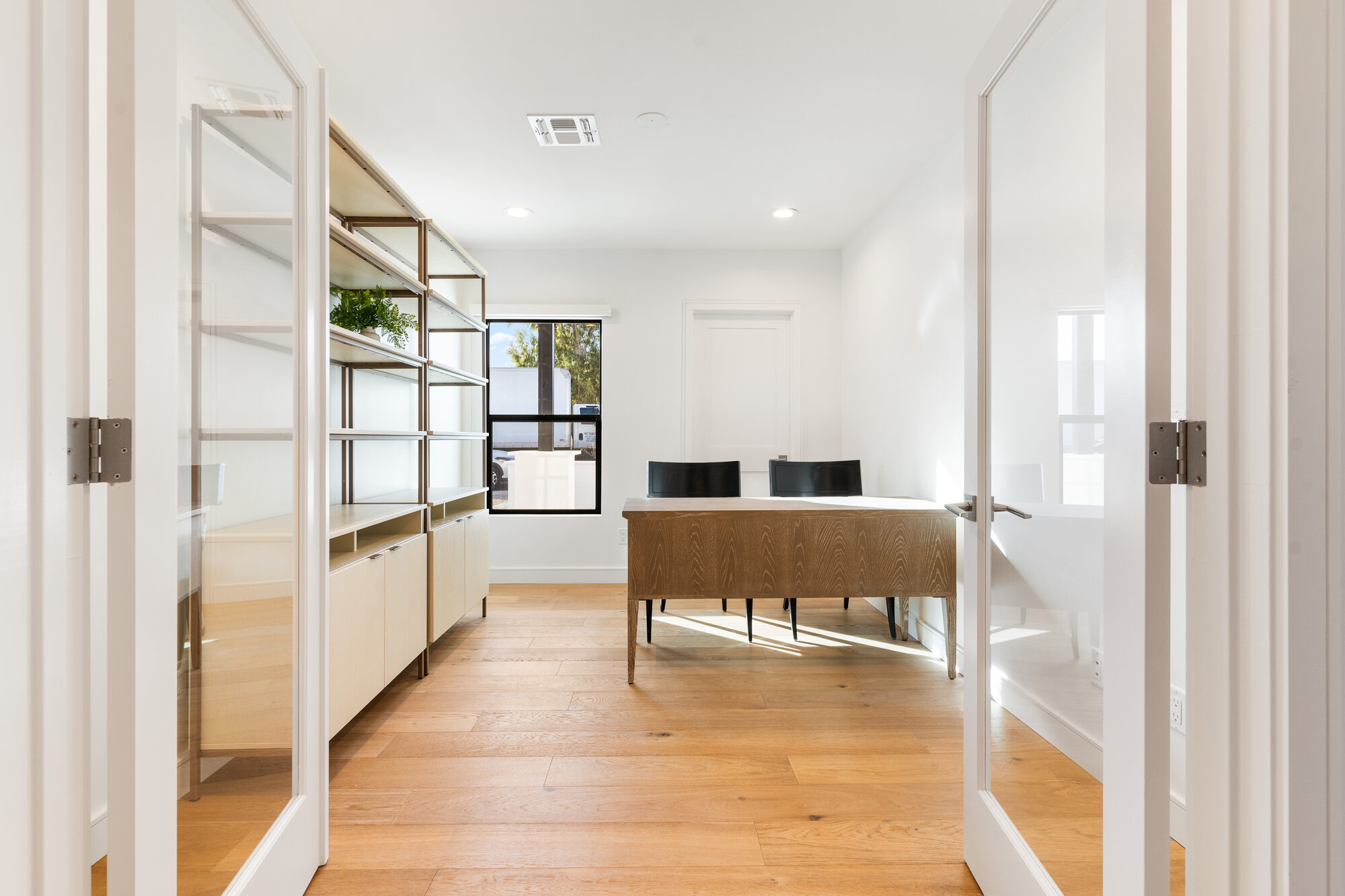 Bright home office with glass doors and hardwood flooring in Scottsdale remodel by Trinity Homes