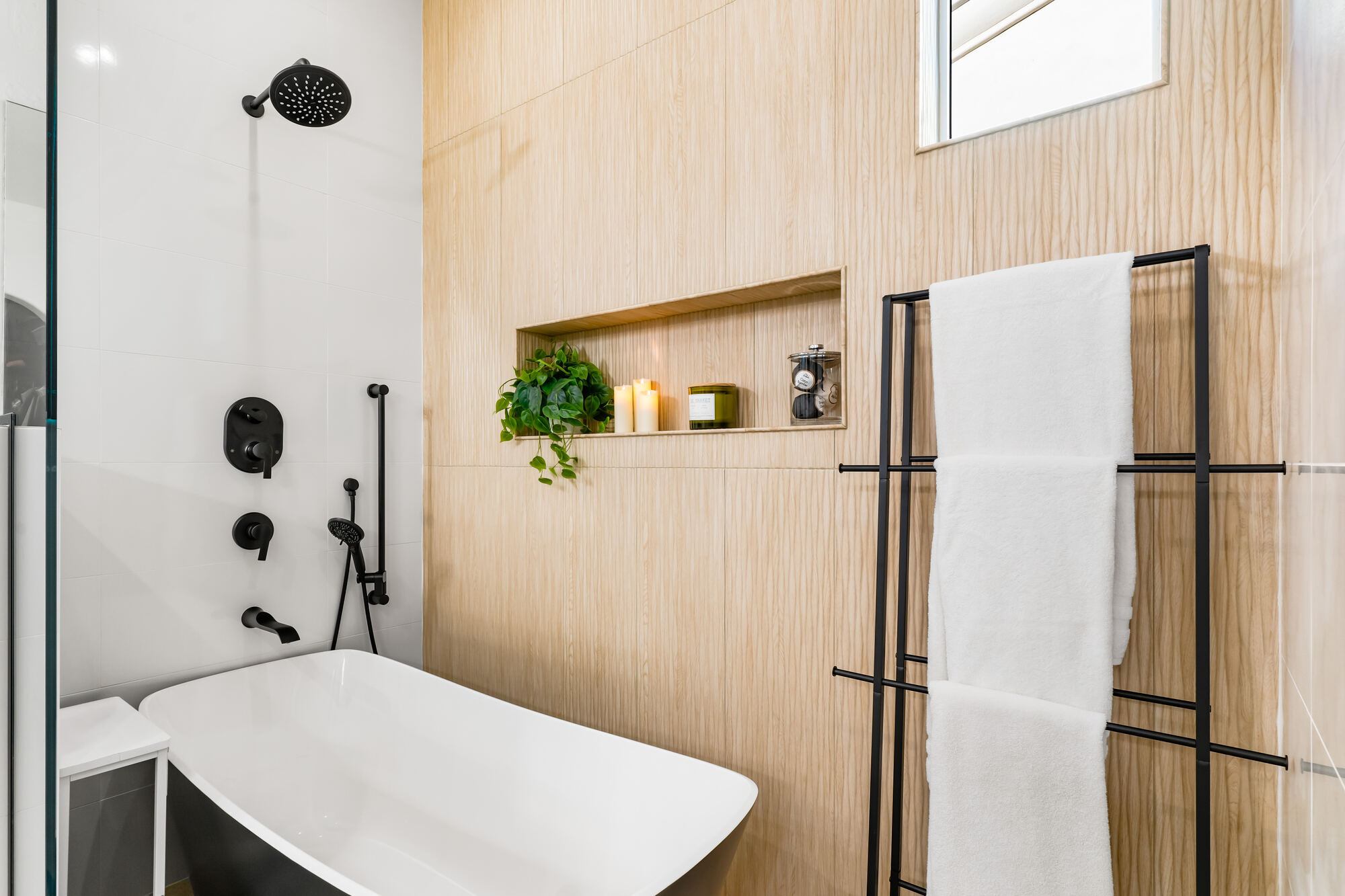 Master bathroom with black freestanding tub and modern niche lighting by Trinity Homes in Phoenix