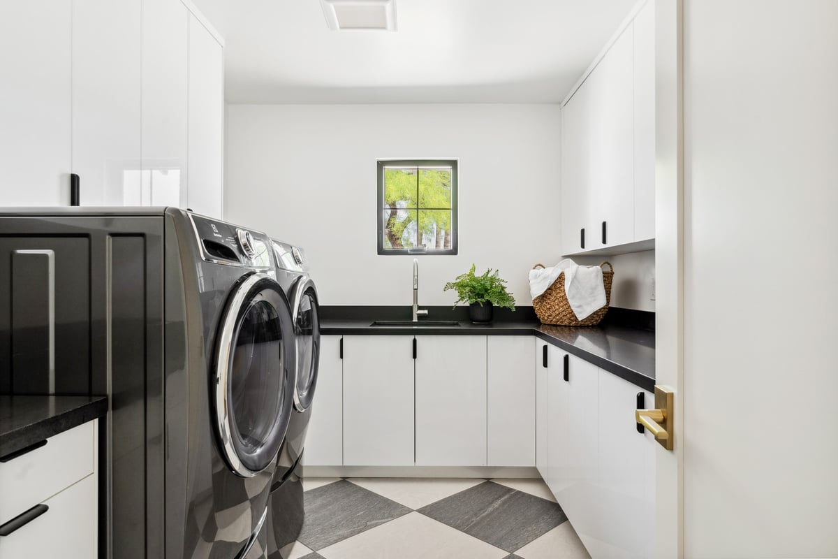 Contemporary laundry room in Scottsdale AZ remodel by Trinity Homes with black countertops