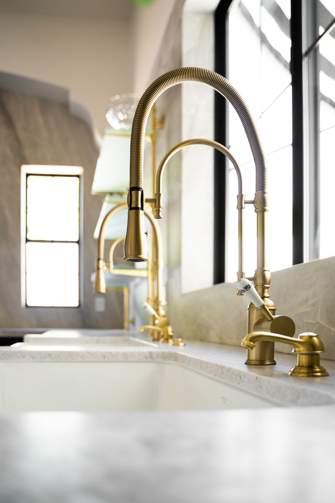 Double farmhouse sink with brass fixtures and glass shelving in Scottsdale kitchen remodel by Trinity Homes
