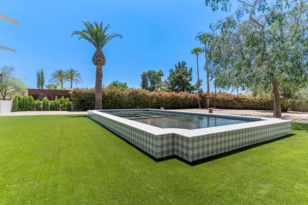 Geometric tiled backyard pool surrounded by lush landscaping in Phoenix whole home remodel by Trinity Homes