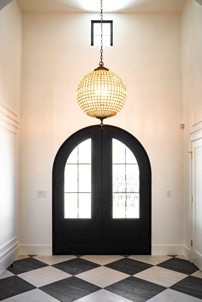 Grand entryway with black double doors and globe chandelier in Scottsdale remodel by Trinity Homes