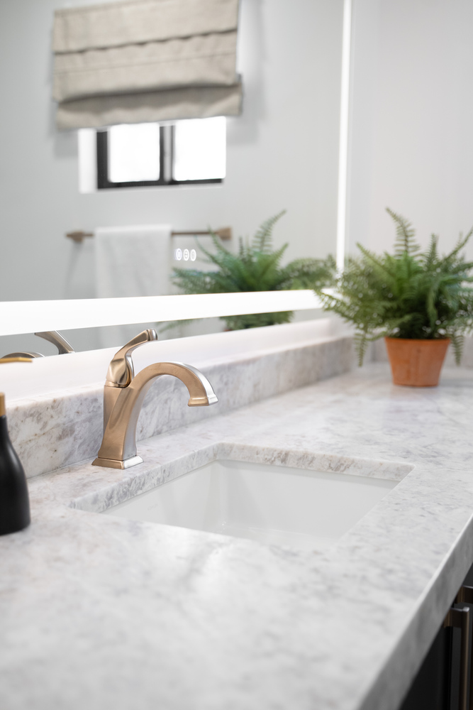 Modern bathroom sink with brushed brass faucet and marble countertop by Trinity Homes in Phoenix remodel