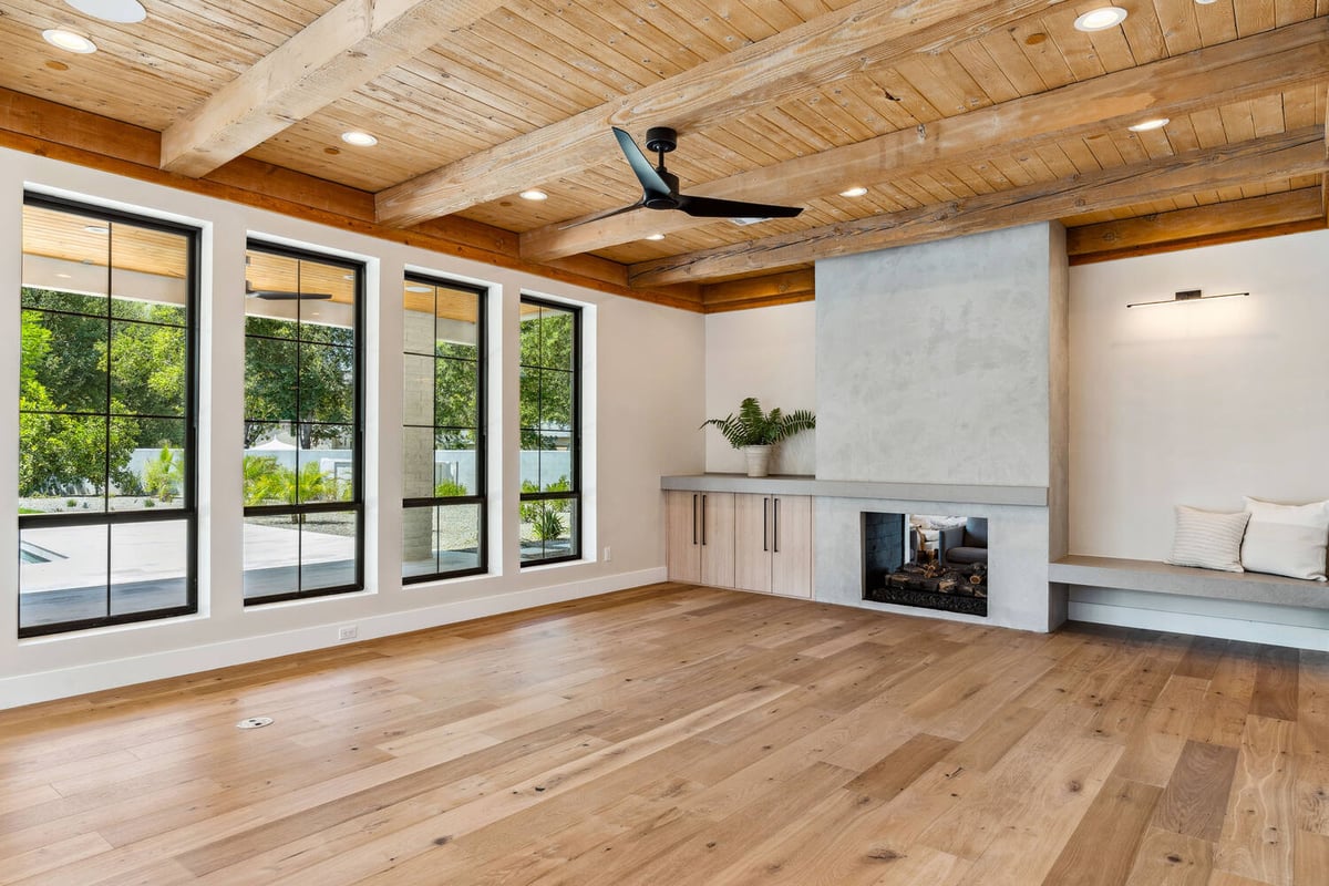 Large living room with expansive windows and rustic ceiling detail by Trinity Homes in Paradise Valley