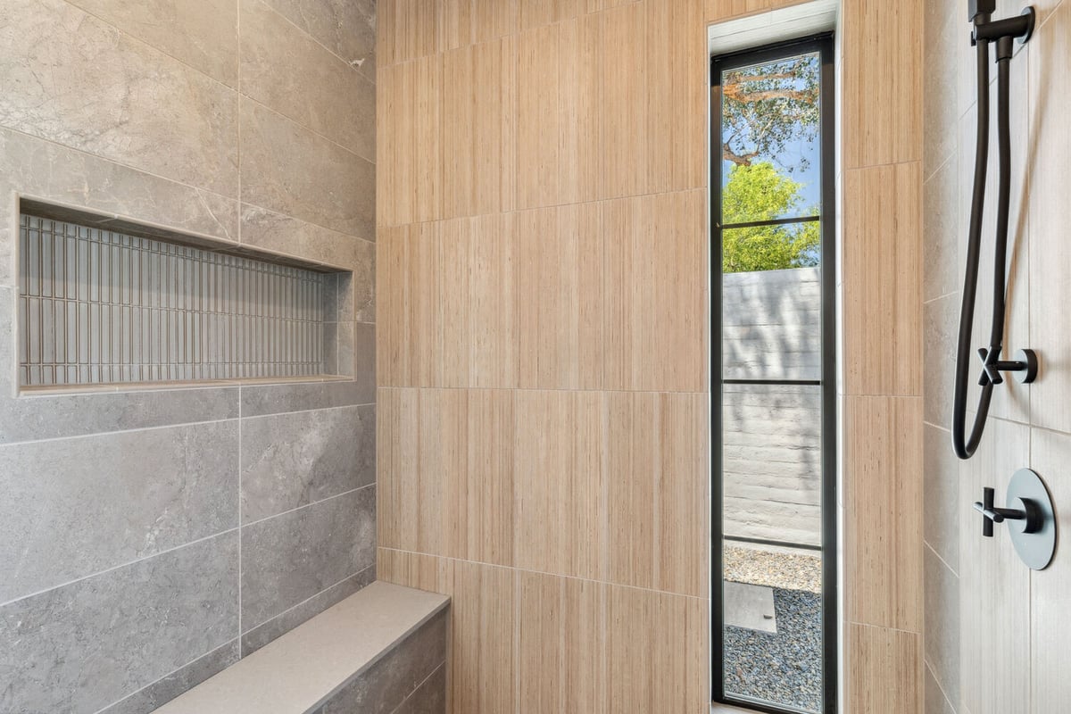 Neutral shower with bench seating and vertical tile detail by Trinity Homes in Paradise Valley