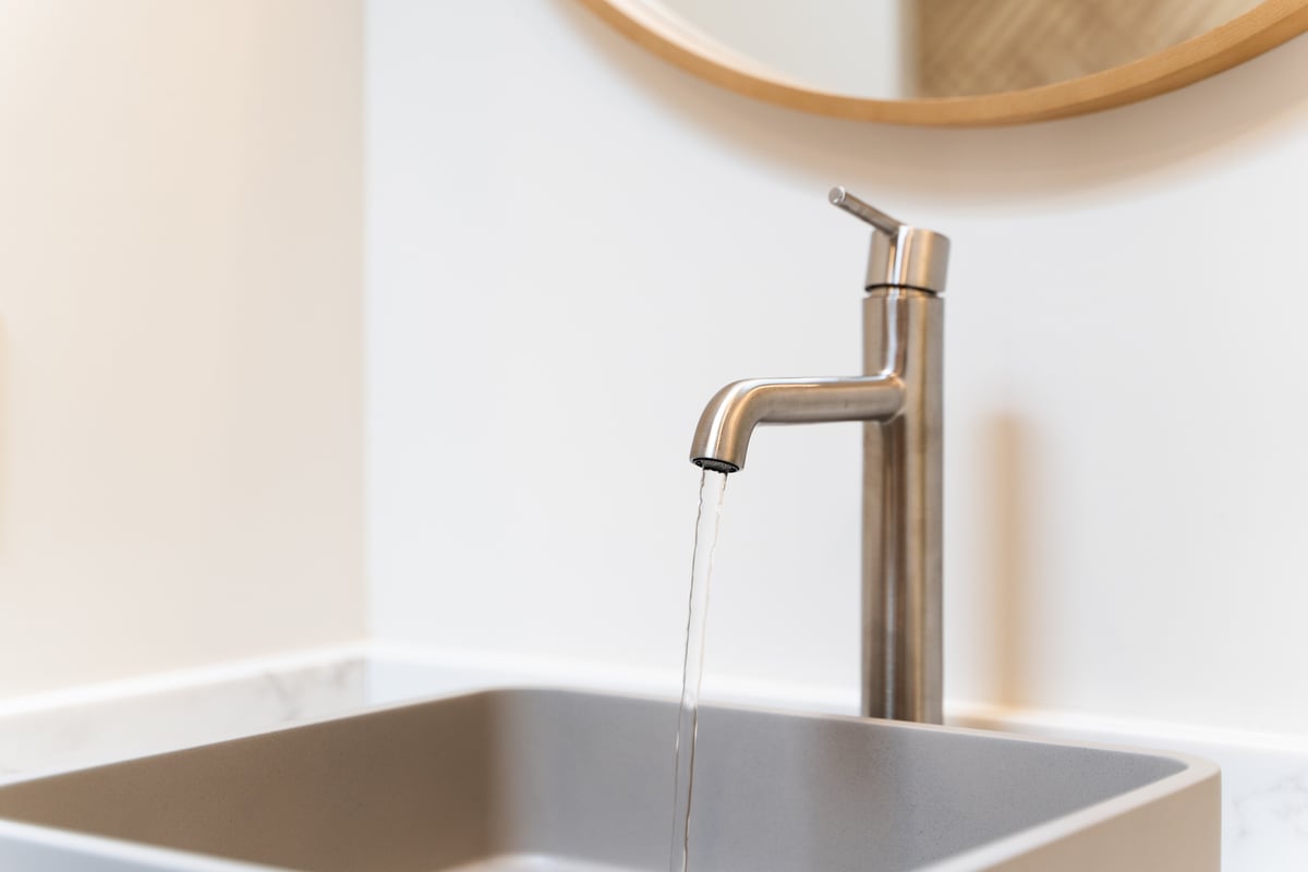Running water from a minimalist faucet over a square sink in Trinity Homes’ Paradise Valley bathroom
