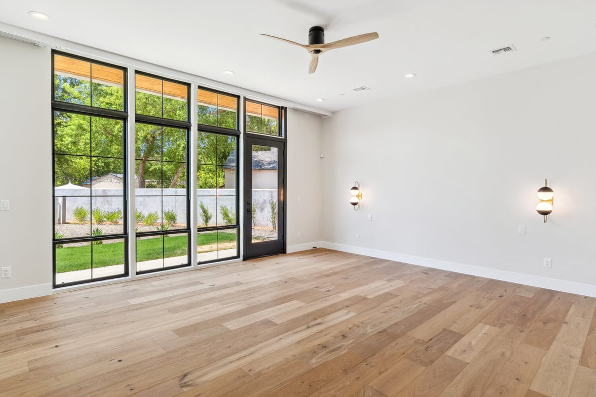 Spacious living room with modern light fixture and black French doors by Trinity Homes in Paradise Valley