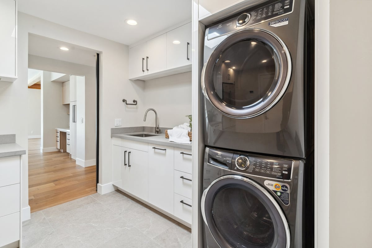 Utility room with built-in sink and stacked laundry machines in Paradise Valley remodel by Trinity Homes