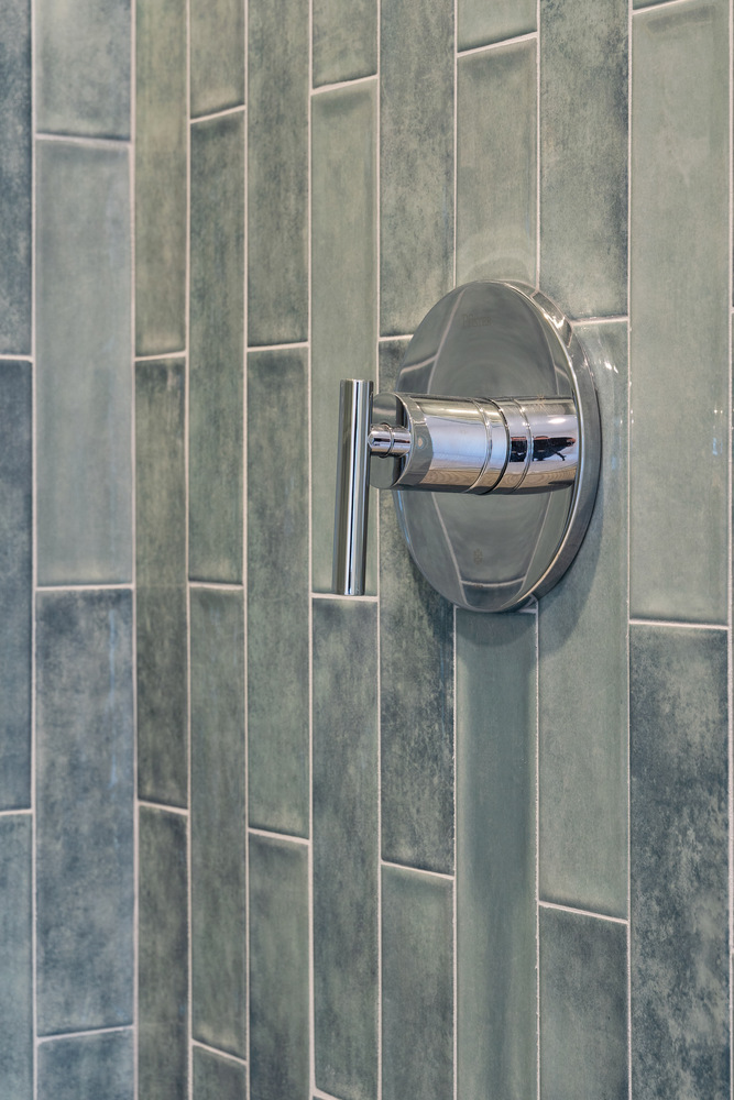 Chrome shower control handle on green tile wall in Scottsdale home renovated by Trinity Homes