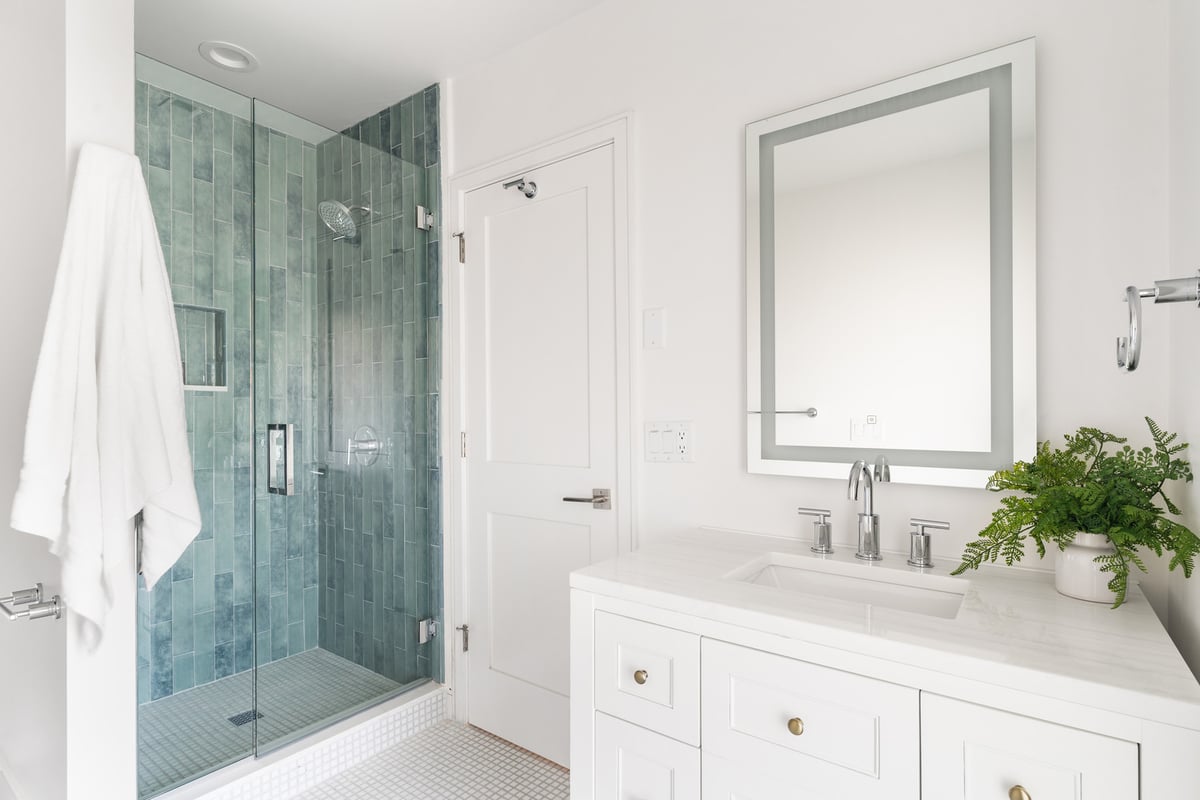 Elegant white bathroom with green tile walk-in shower in a Scottsdale home renovation by Trinity Homes