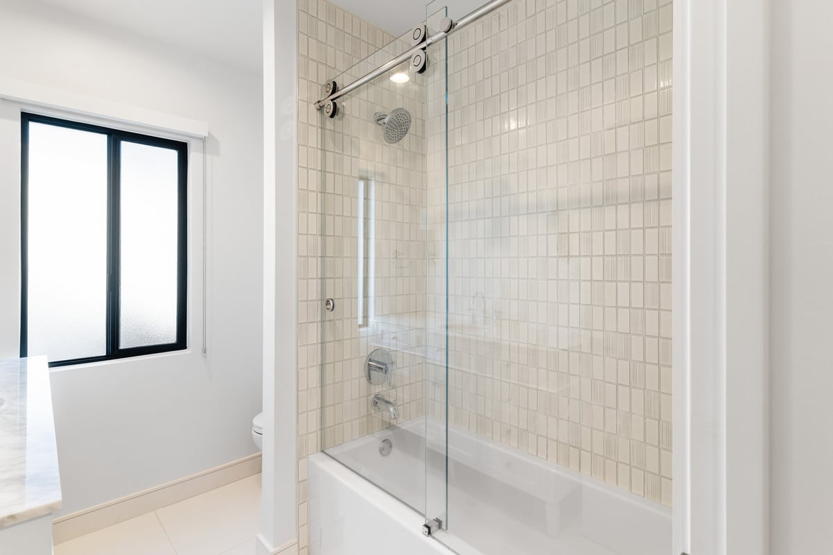 Modern shower with glass door and beige tile wall in Scottsdale bathroom remodel by Trinity Homes