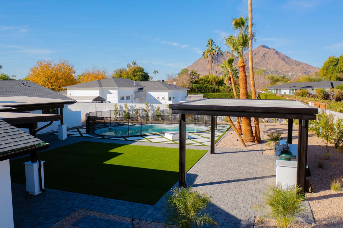 Trinity Homes backyard remodel in Scottsdale, AZ featuring a covered grill area, pool, and Camelback Mountain views