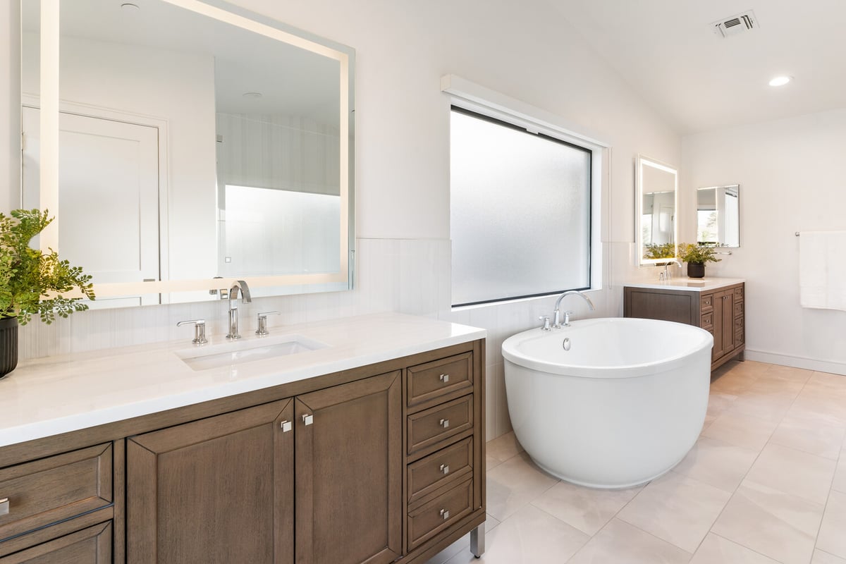 Warm-toned vanity and backlit mirror in a custom bathroom remodel by Trinity Homes in Scottsdale