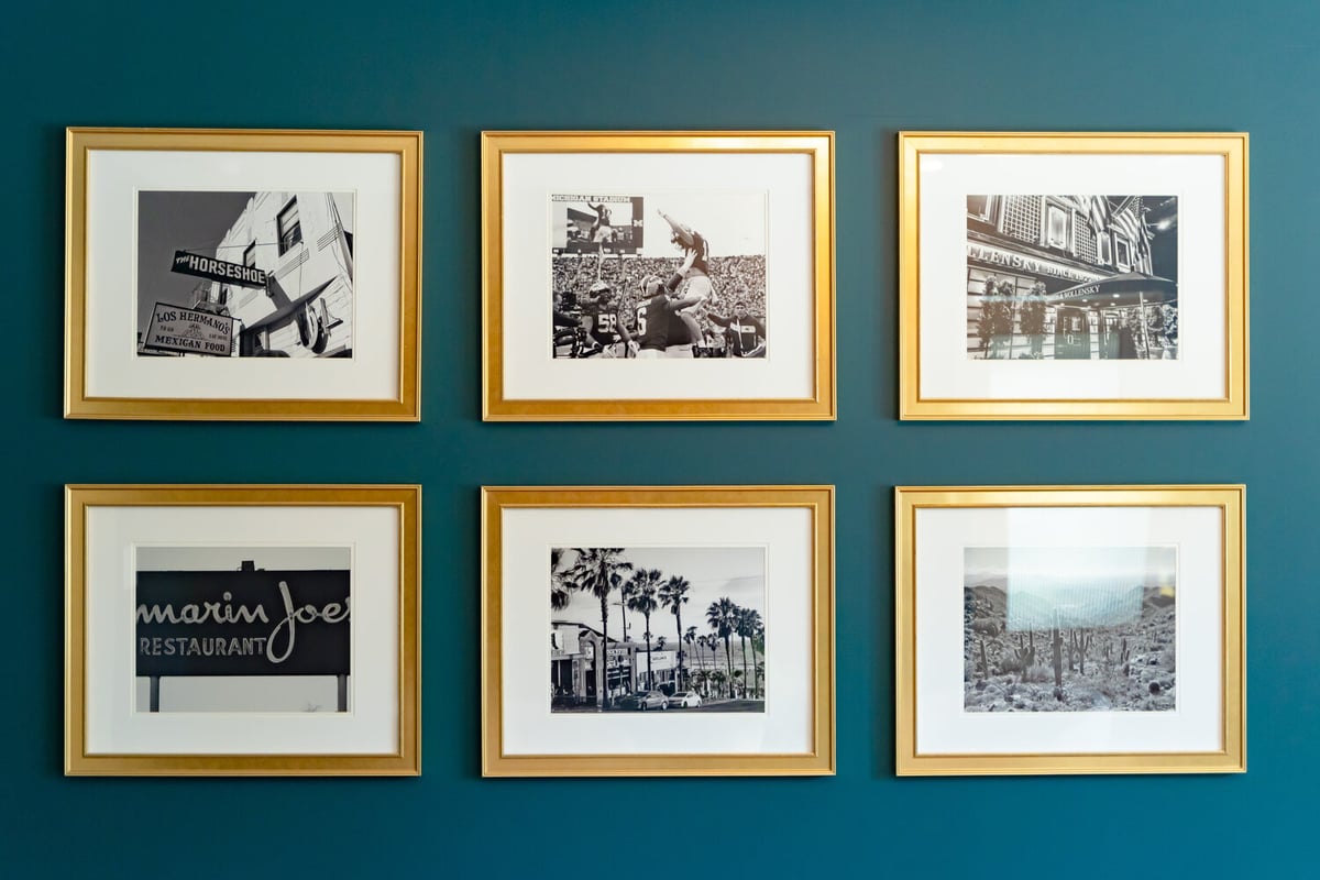 Artistic gallery wall with gold frames on deep teal background by Trinity Homes AZ in Paradise Valley, AZ