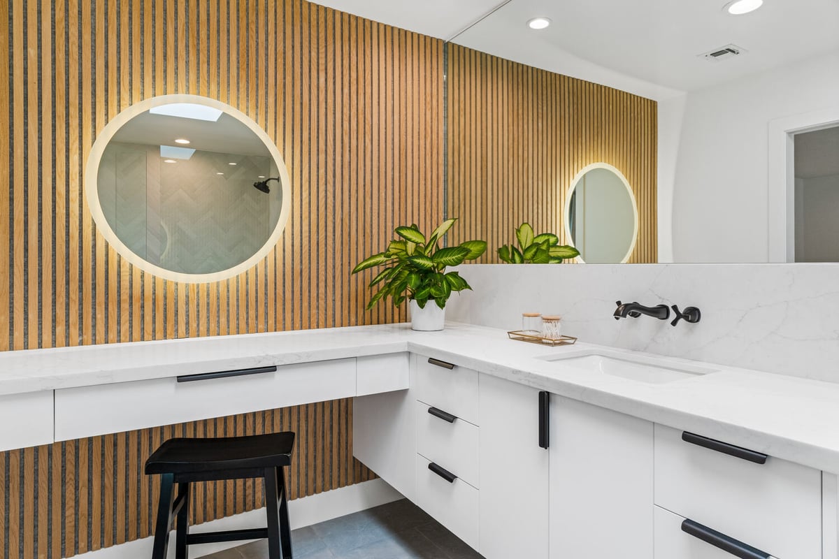 Dual vanity and makeup station with wood accent wall in a custom bathroom by Trinity Homes AZ in Tempe, AZ