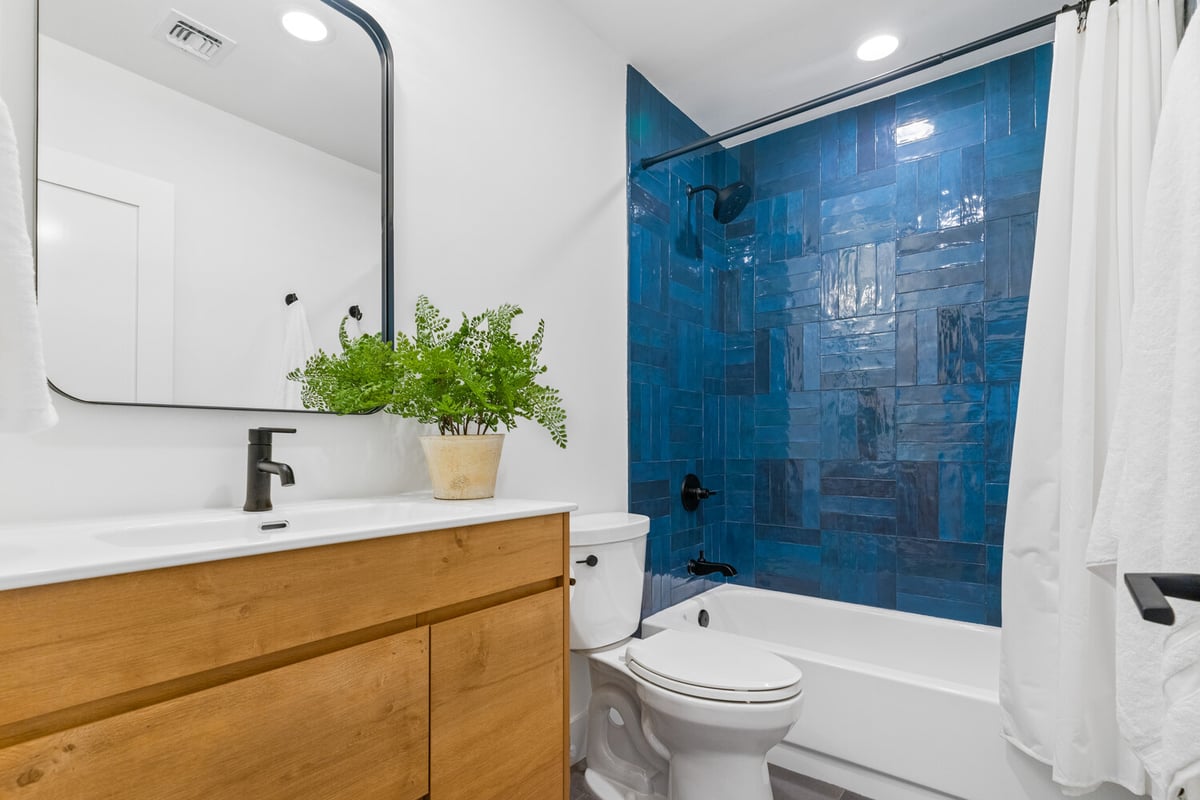Guest bathroom with blue tile shower and wood vanity designed by Trinity Homes AZ in Arcadia, AZ