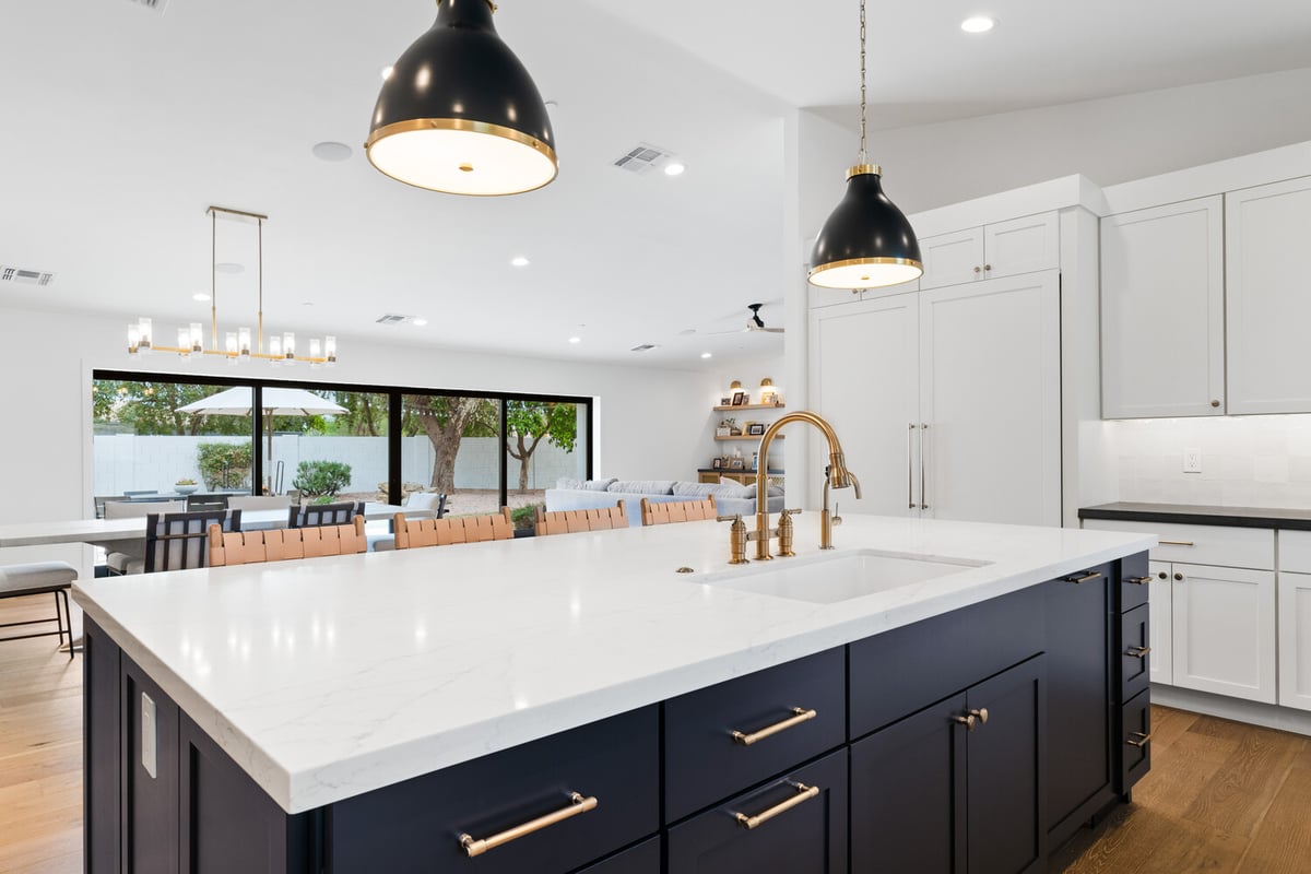 Kitchen island with brass faucet and living room view by Trinity Homes AZ in Arcadia, AZ
