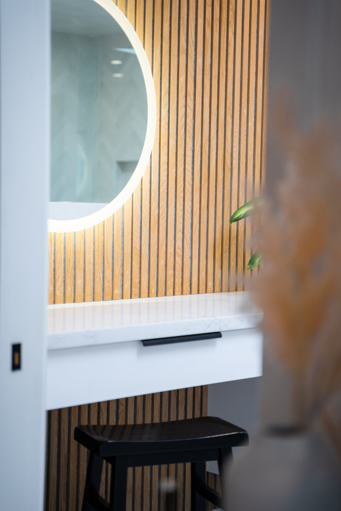 Modern makeup station with LED mirror and vertical wood slats by Trinity Homes AZ in Cave Creek, AZ
