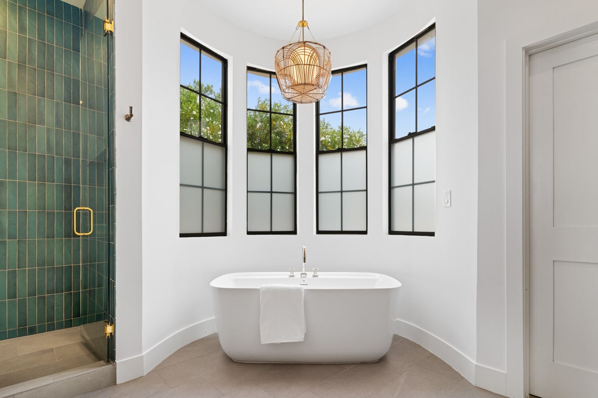 Modern master bathroom with soaking tub and black-framed windows by Trinity Homes AZ in Arcadia, AZ