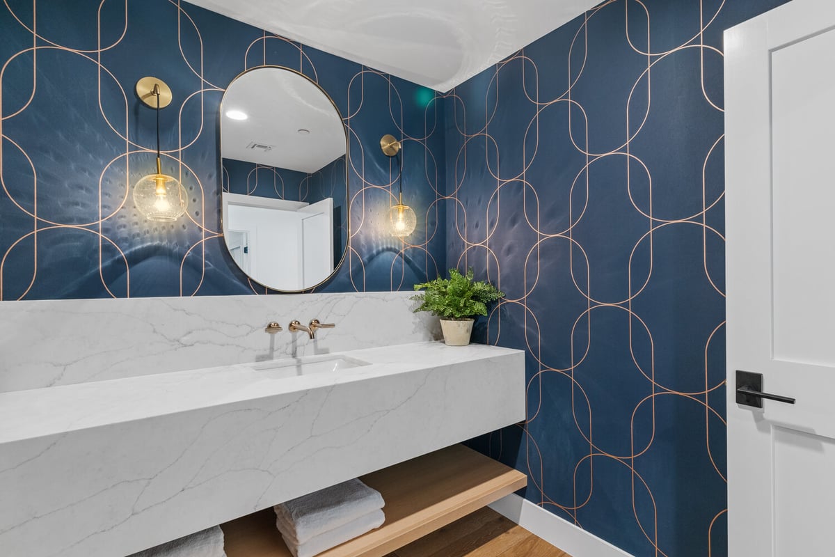 Powder room with marble vanity and gold sconces on navy geometric wallpaper by Trinity Homes AZ in Phoenix, AZ