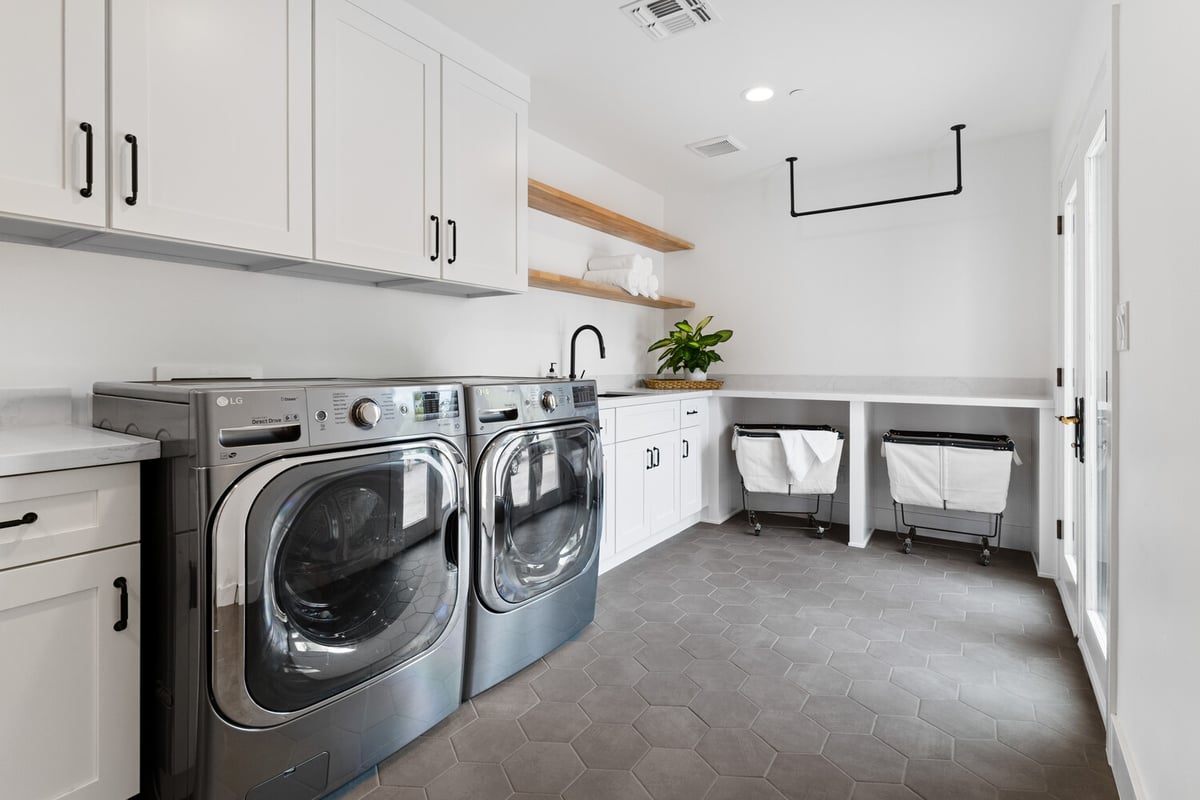 Spacious laundry room with double washer-dryer and white cabinetry by Trinity Homes AZ in North Peoria, AZ