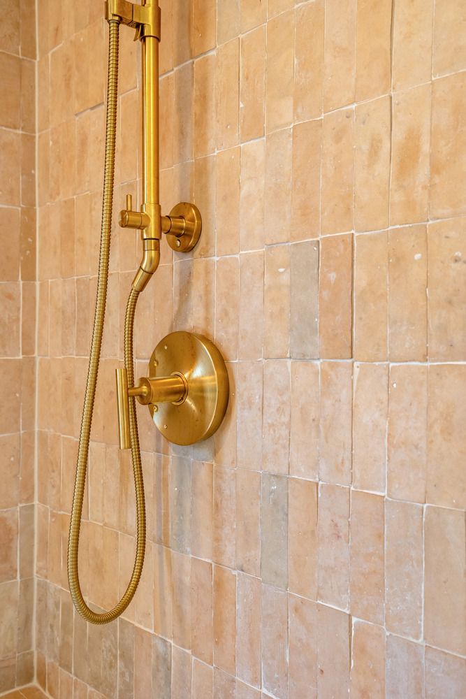 Close-up of dual vanity with white marble counter and wall-mounted brass faucets in Scottsdale custom home