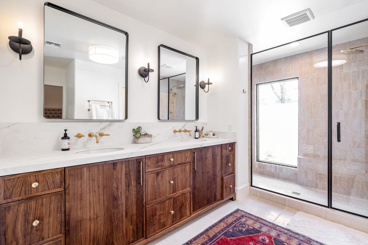 Dual-sink bathroom with black countertop and gold faucet in custom home by Trinity Homes in Scottsdale