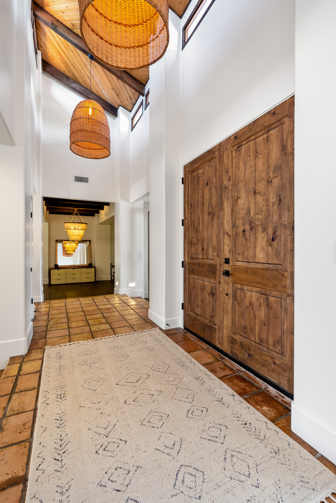 Entryway with wood double doors, terracotta tile, and pendant lighting in a Scottsdale custom home by Trinity Homes