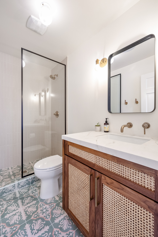 Guest bathroom with decorative tile flooring and rattan vanity in a custom Scottsdale home by Trinity Homes