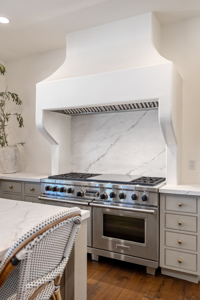 Luxury kitchen range with custom plaster hood and marble backsplash by Trinity Homes in Scottsdale
