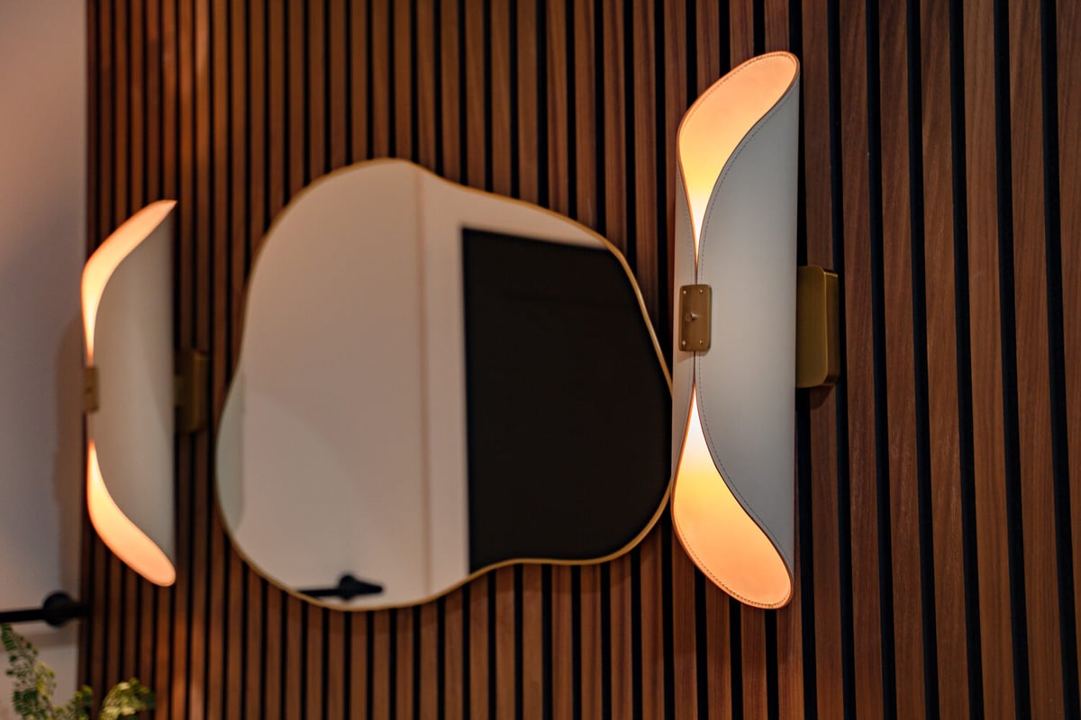 Close-up of sculptural wall sconce and irregular mirror on slat wall in Scottsdale home by Trinity Homes