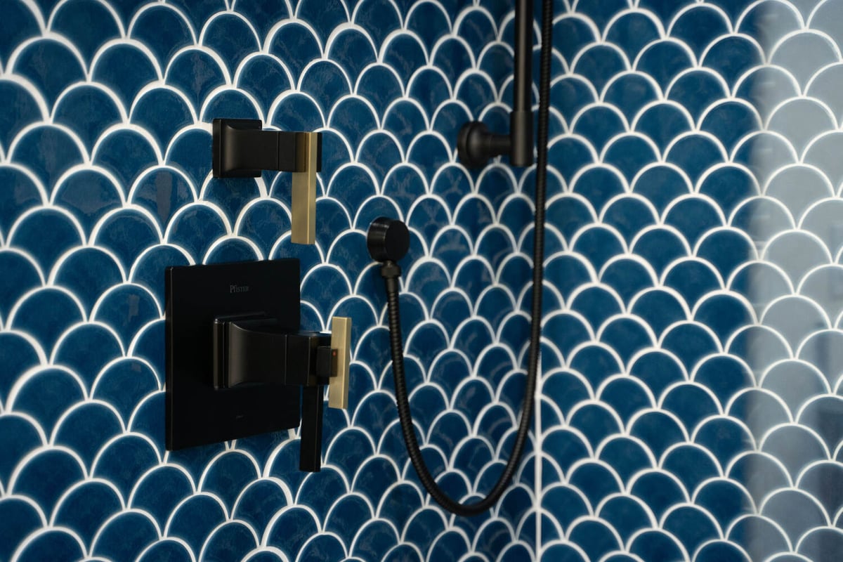Matte black and gold shower hardware on blue scallop tile wall in Trinity Homes Scottsdale remodel