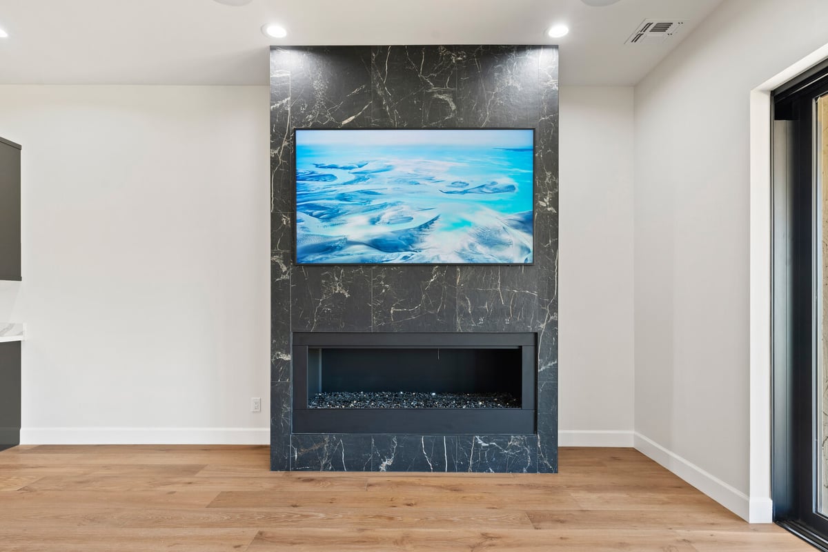Modern living area with black marble fireplace and mounted TV in Trinity Homes remodel, Scottsdale, AZ