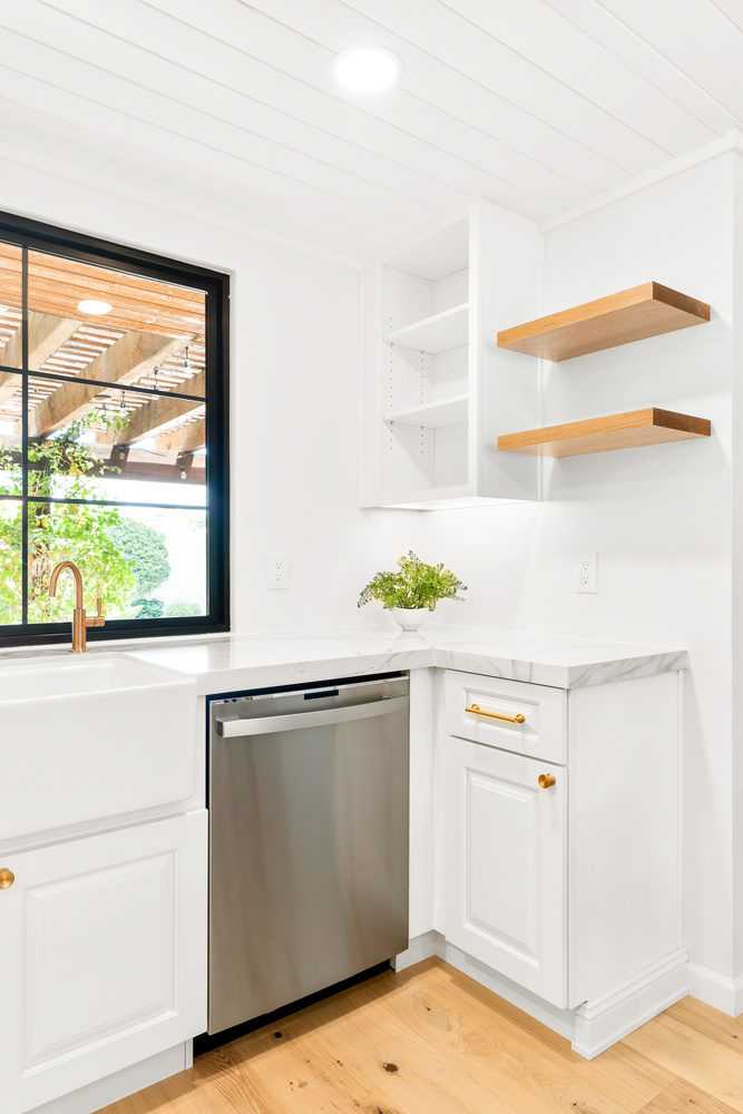 Corner view of custom white kitchen with open shelving in a Chandler, AZ home by Trinity Homes AZ