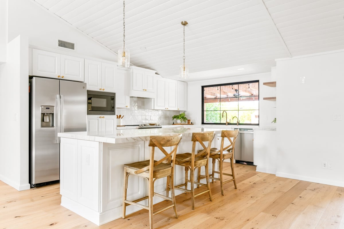 Kitchen island with wood stools and pendant lighting in a custom home by Trinity Homes AZ in Chandler, AZ