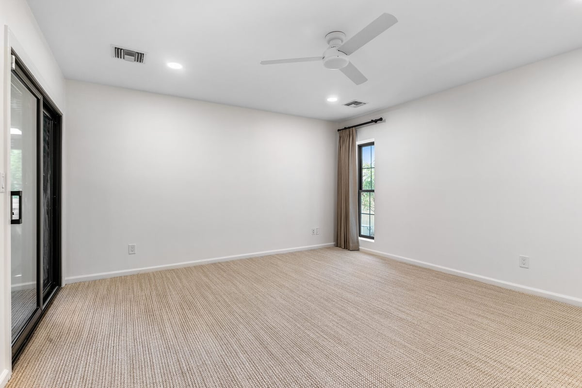 Spacious custom bedroom with natural woven carpet and white ceiling fan in Scottsdale, AZ by Trinity Homes AZ