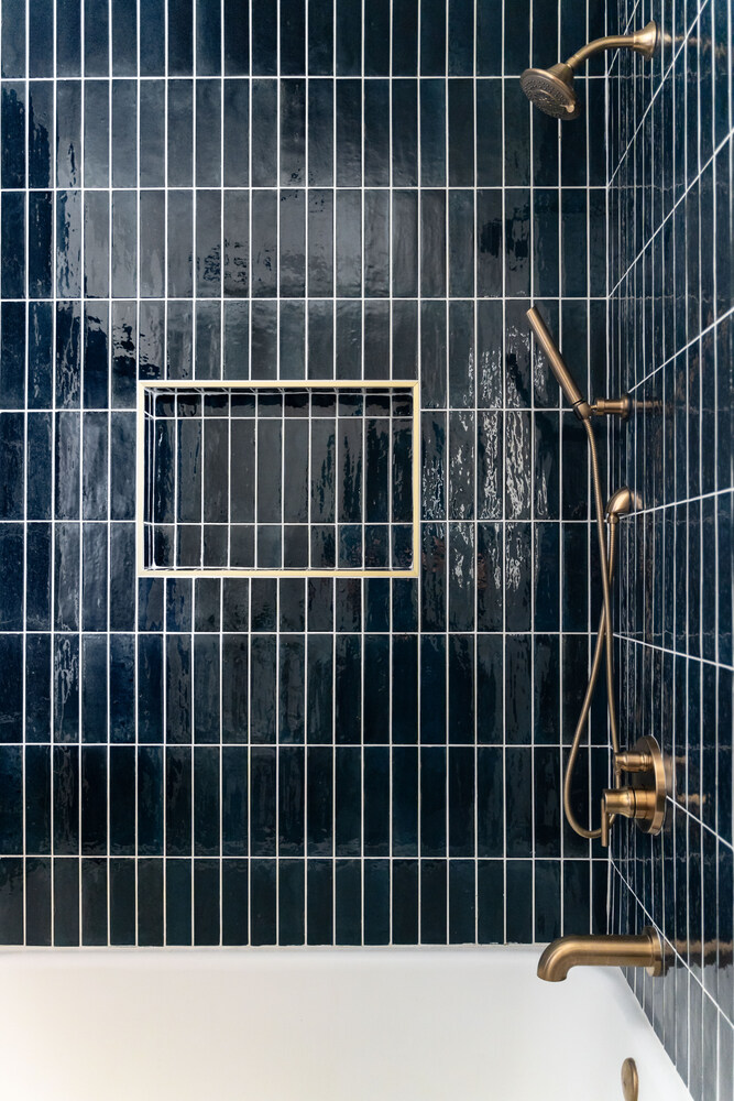 Custom shower with vertical navy tiles and brushed gold fixtures by Trinity Homes AZ in Scottsdale, AZ