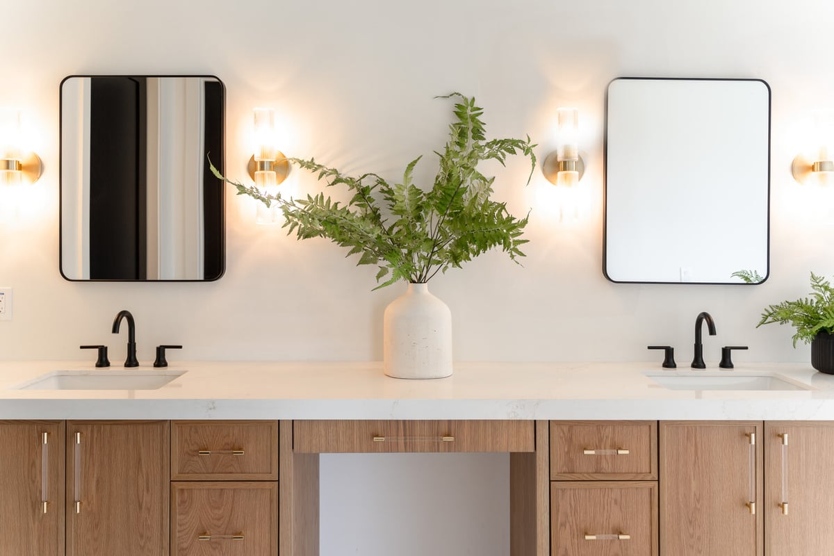 Double sink bathroom vanity with wood cabinets and decorative lighting by Trinity Homes AZ in Scottsdale, AZ