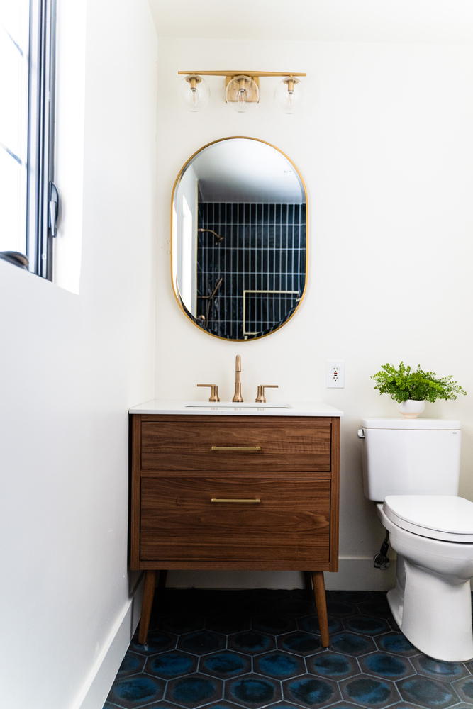 Mid-century modern bathroom vanity with gold fixtures and navy tile accents by Trinity Homes AZ in Scottsdale, AZ