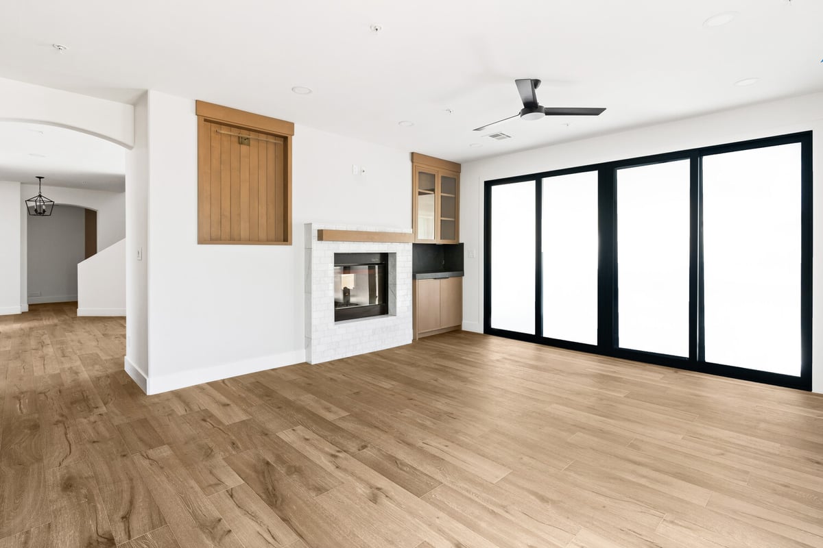 Bright family room with black sliding doors and modern ceiling fan in Mesa, AZ by Trinity Homes AZ