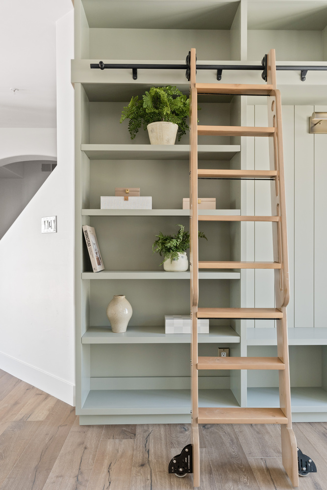 Built-in storage wall with natural wood ladder in a Trinity Homes AZ custom home in Glendale, AZ