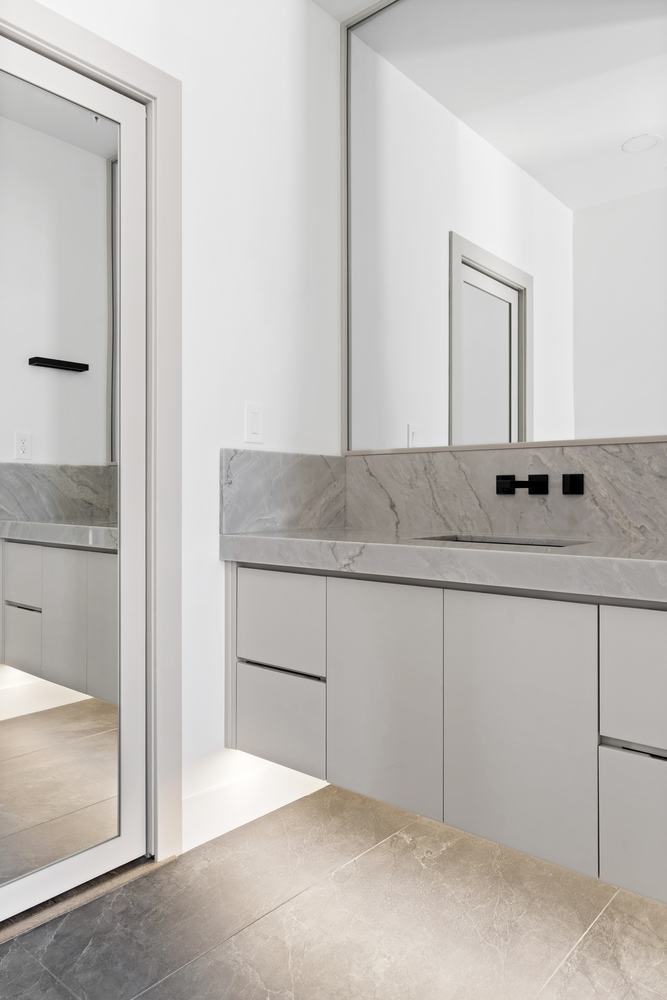 Custom floating vanity with large wall mirror and marble backsplash by Trinity Homes AZ in Tempe, AZ