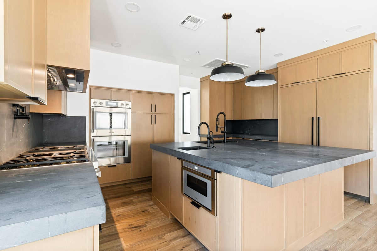 Custom kitchen with black quartz countertops and natural wood cabinetry by Trinity Homes AZ in Cave Creek, AZ