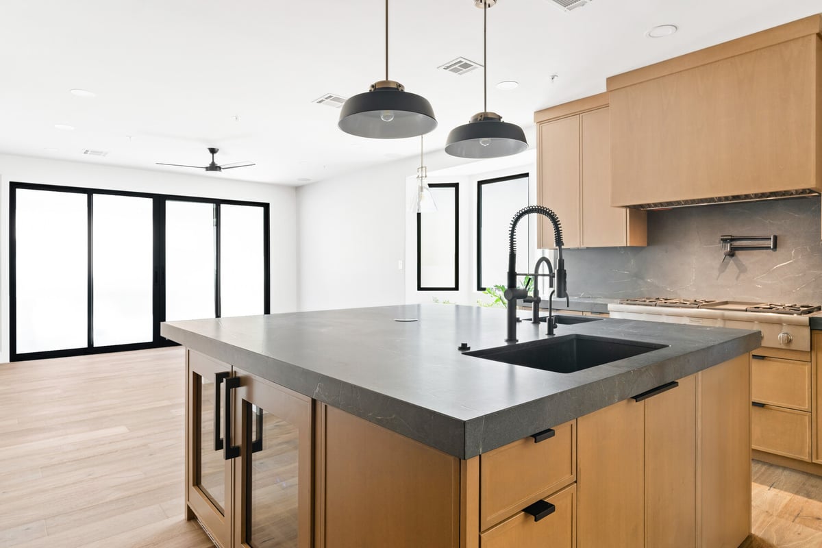 Open-concept kitchen and living space featuring black countertops in a Mesa, AZ remodel by Trinity Homes AZ