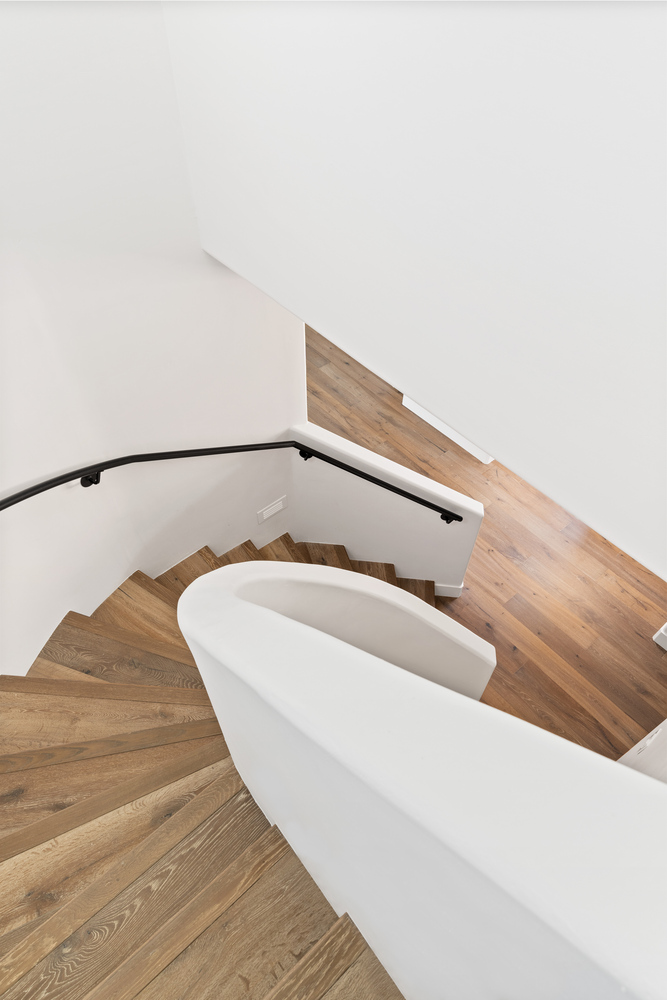 Scottsdale custom home stairwell with smooth curved railing and hardwood floors by Trinity Homes AZ